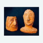 Due teste scultoree in terracotta su fondo scuro